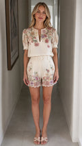 Front view of woman wearing off-white floral top and matching shorts set