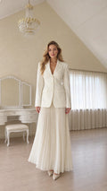 Full length view of a woman wearing a white tailored blazer and pleated skirt