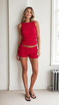 Model wearing the red textured crop top and ruffle shorts set, front view