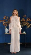 Front view of model wearing champagne cold-shoulder overlay jumpsuit