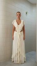 Front view of model wearing ivory ruffled two-piece maxi set