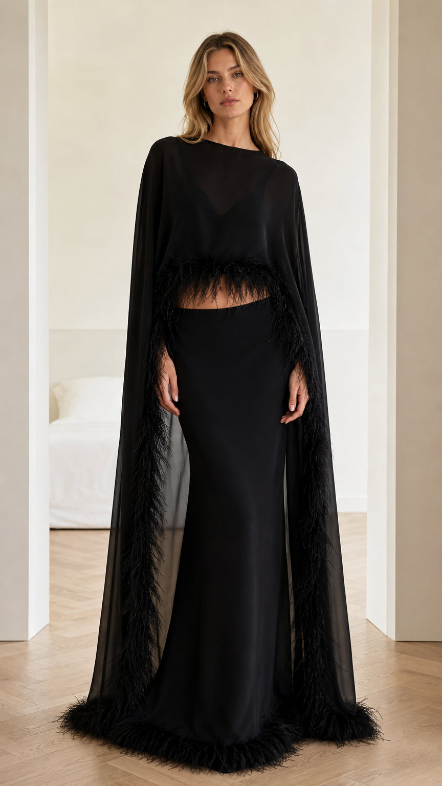 Front view of black two-piece evening gown with feather-trimmed cape top and maxi skirt