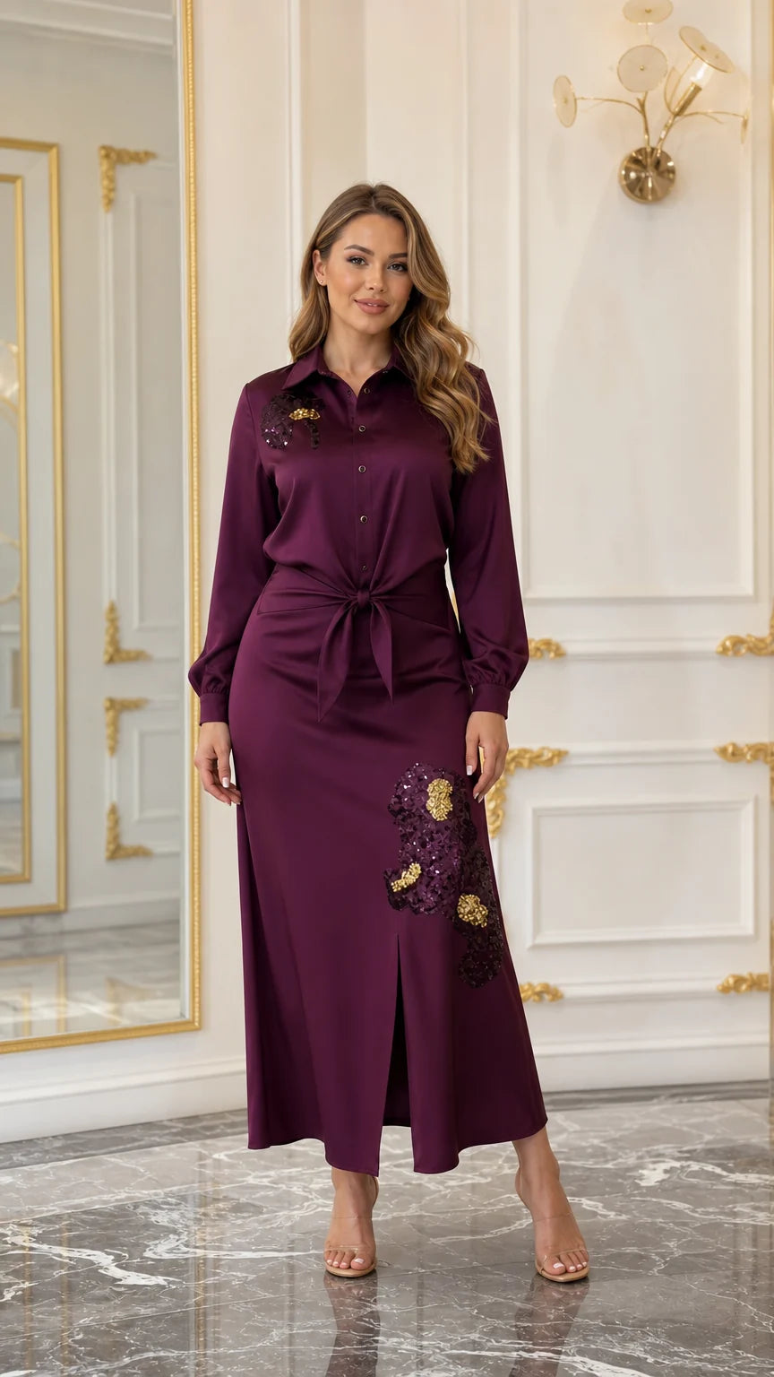 Woman wearing a burgundy satin-look embroidered maxi shirt dress with tie waist and front slit