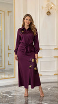 Woman wearing a burgundy satin-look embroidered maxi shirt dress with tie waist and front slit