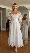 Front view of woman wearing white off-shoulder embroidered midi dress