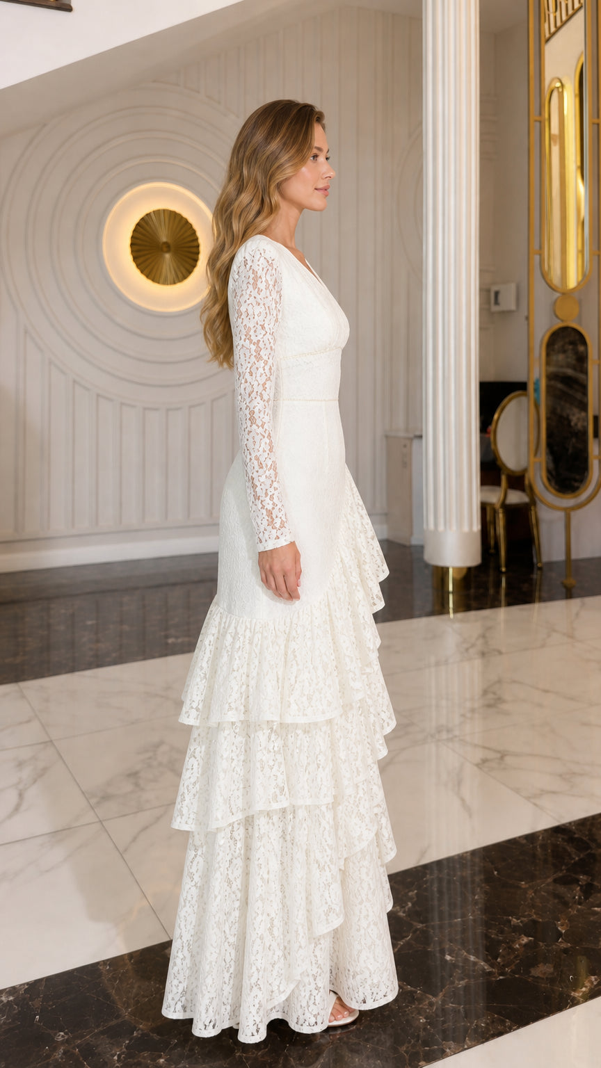 Side profile of model wearing ivory lace maxi gown with tiered ruffles