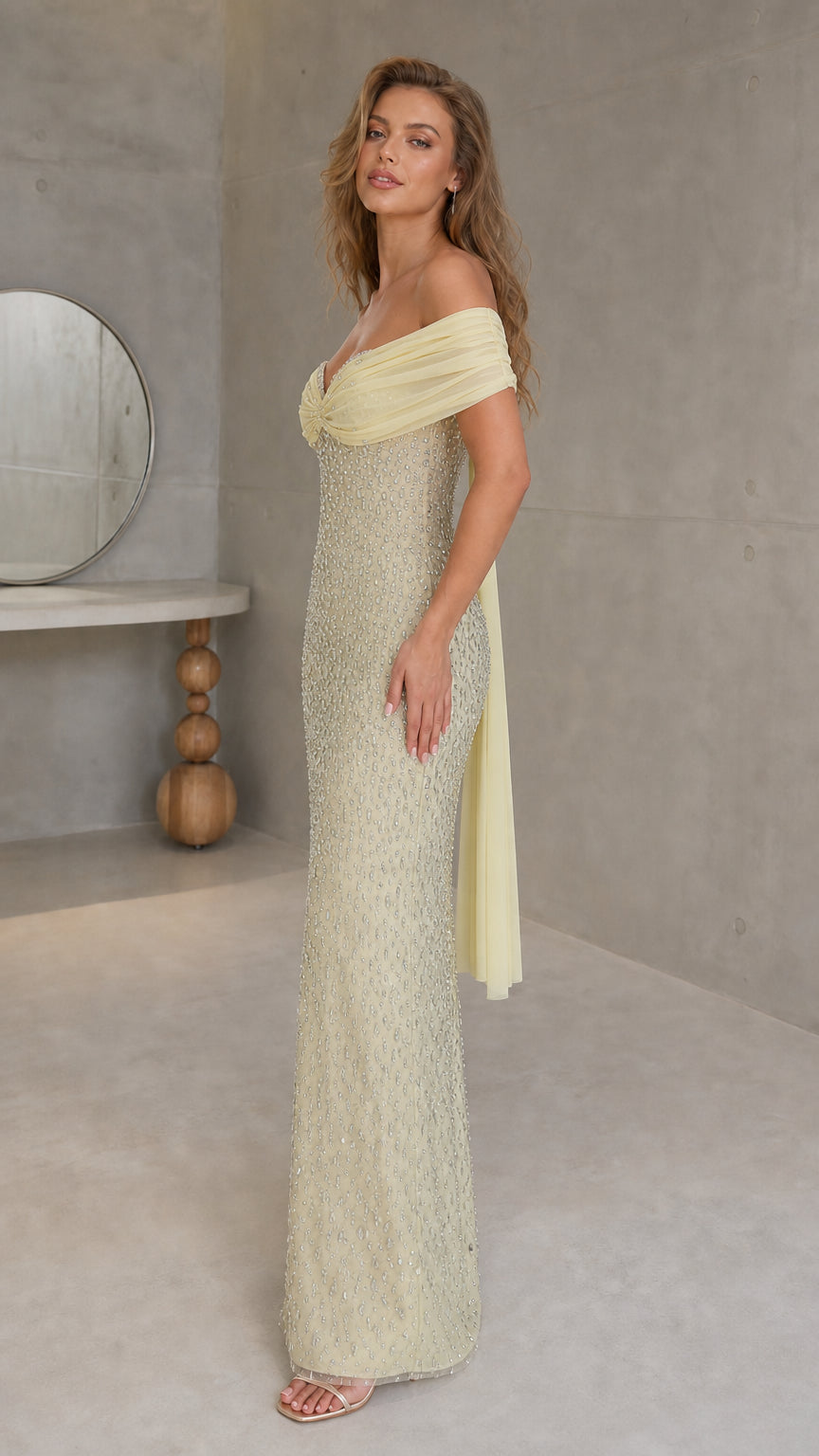 Model wearing yellow evening gown showcasing side profile and draped scarf