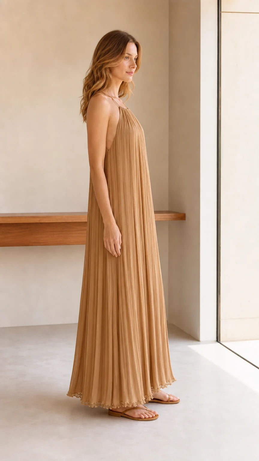 Model wearing camel pleated halter maxi dress, side profile