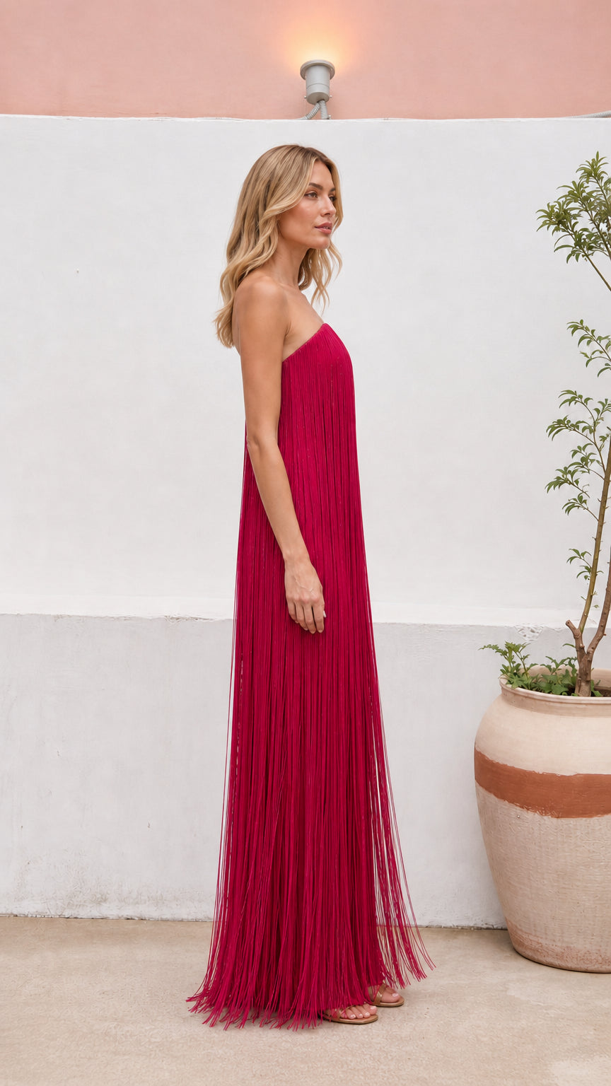 Side profile view of women's strapless tassel maxi gown in magenta