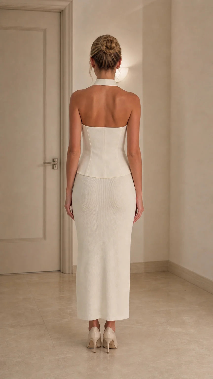 Back view of model wearing ivory halter top and midi skirt