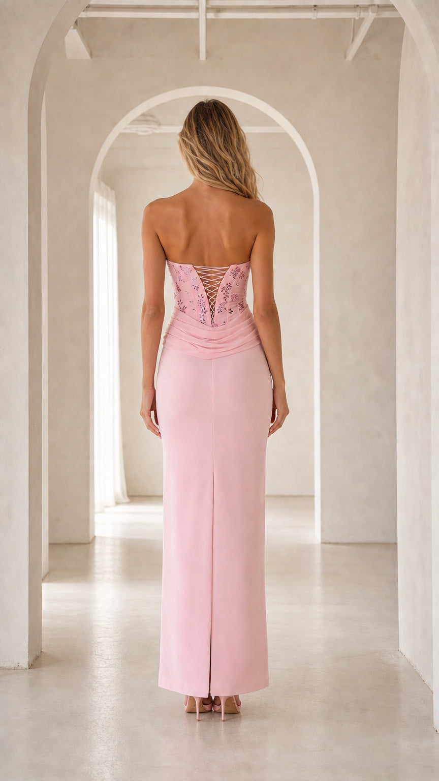 Back view of pink strapless gown showing lace-up corset detail and skirt slit