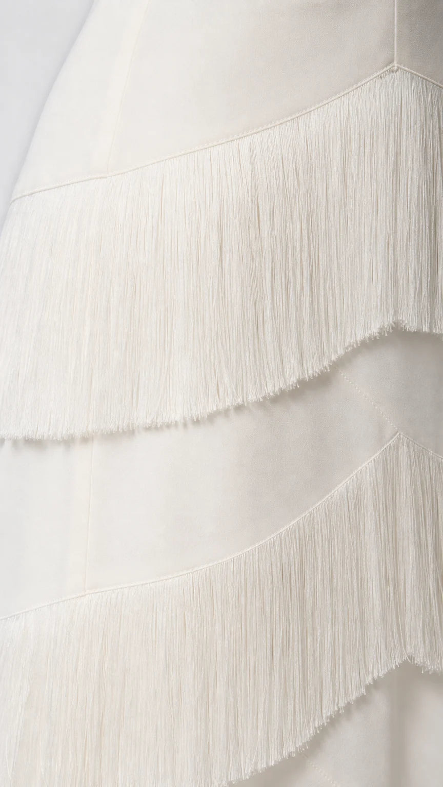 Close-up detail of the fringe texture on the white dress