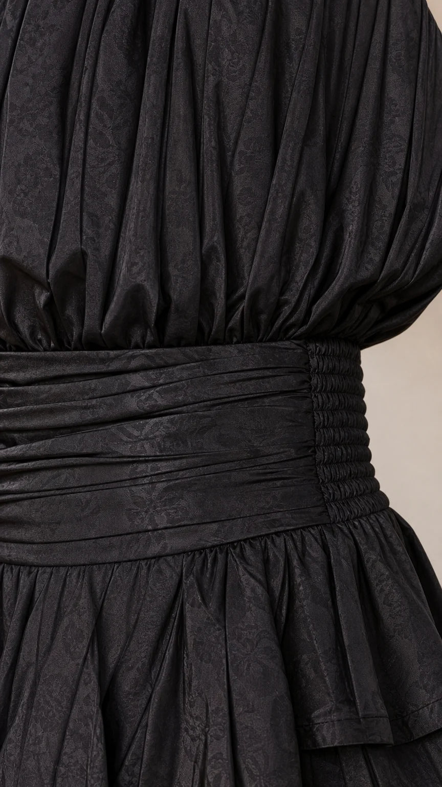 Close-up detail of smocked waist and textured fabric on black romper