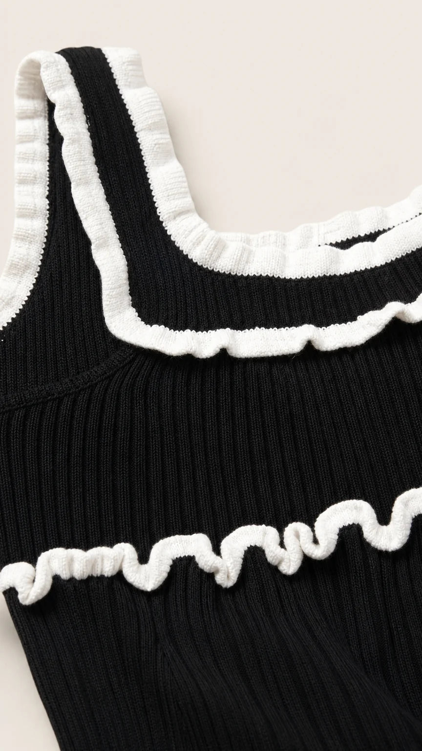 Close-up detail of white lettuce ruffles on black knit top