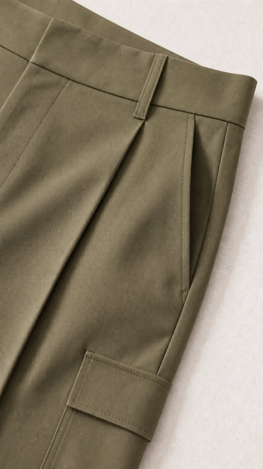 Close-up detail of trousers showing waistband, front pleats, and side cargo flap pocket
