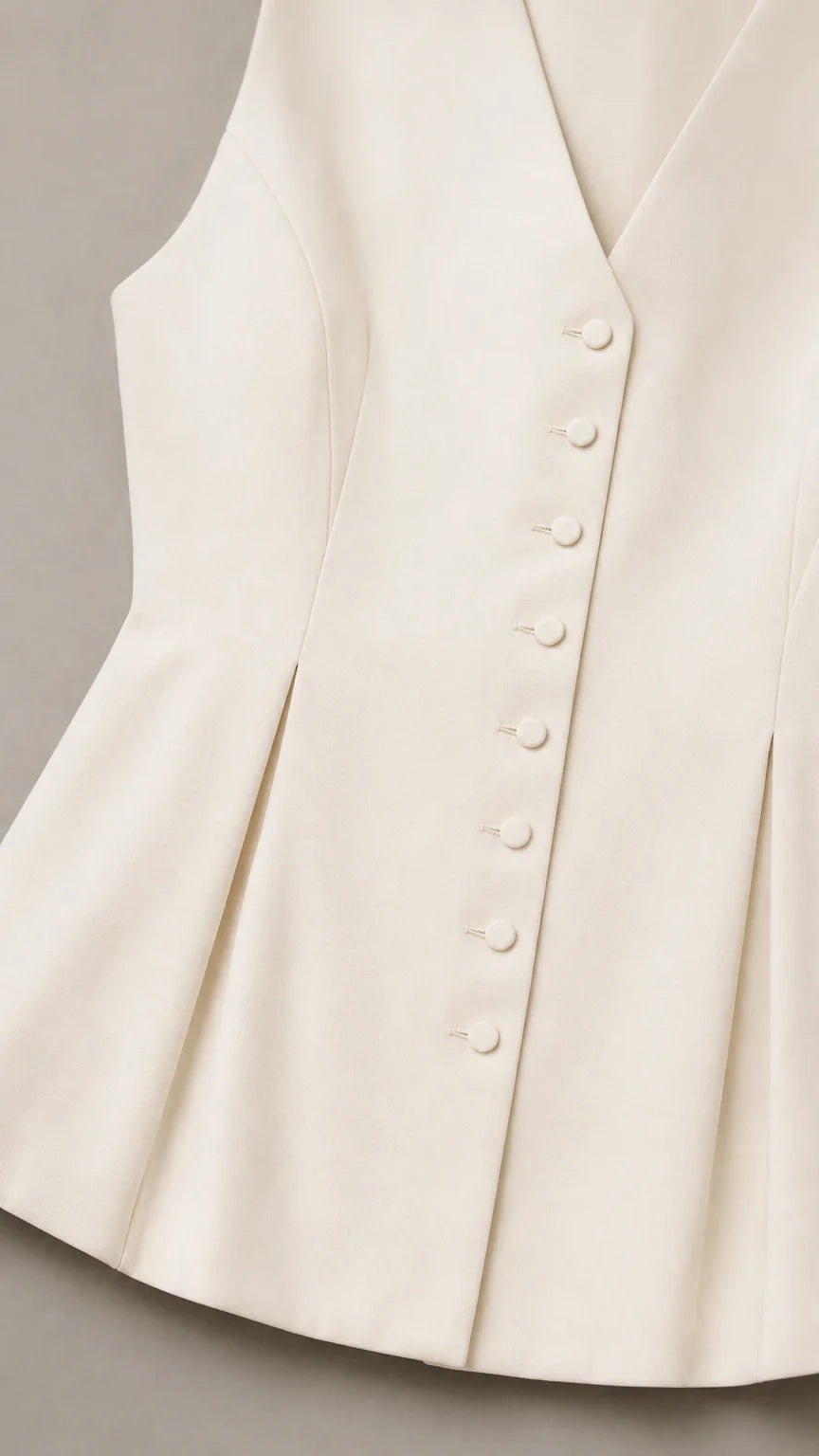 Close up of white vest button details and peplum hem