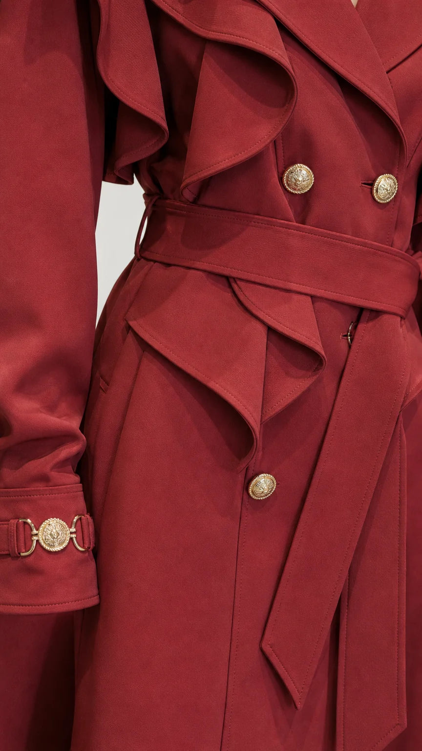 Close-up detail of ruffle capelet and gold buttons on red trench coat