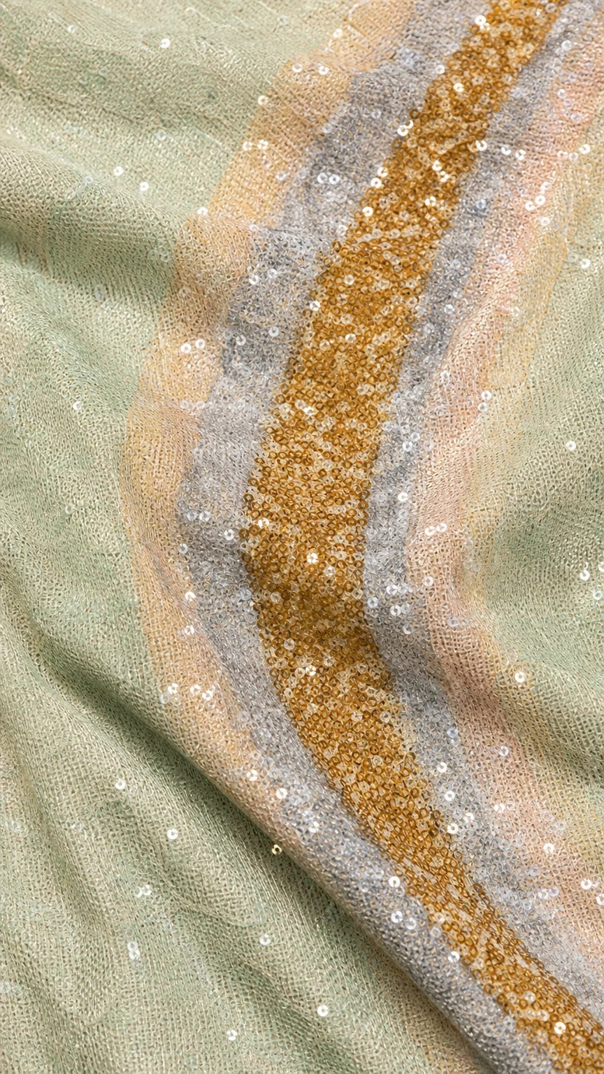 Close-up of gold, silver, and mint sequin wave fabric texture