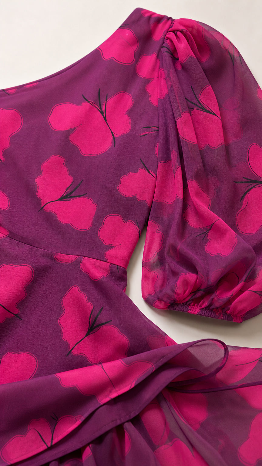 Close-up detail of one-shoulder puff sleeve and sheer magenta butterfly print chiffon fabric