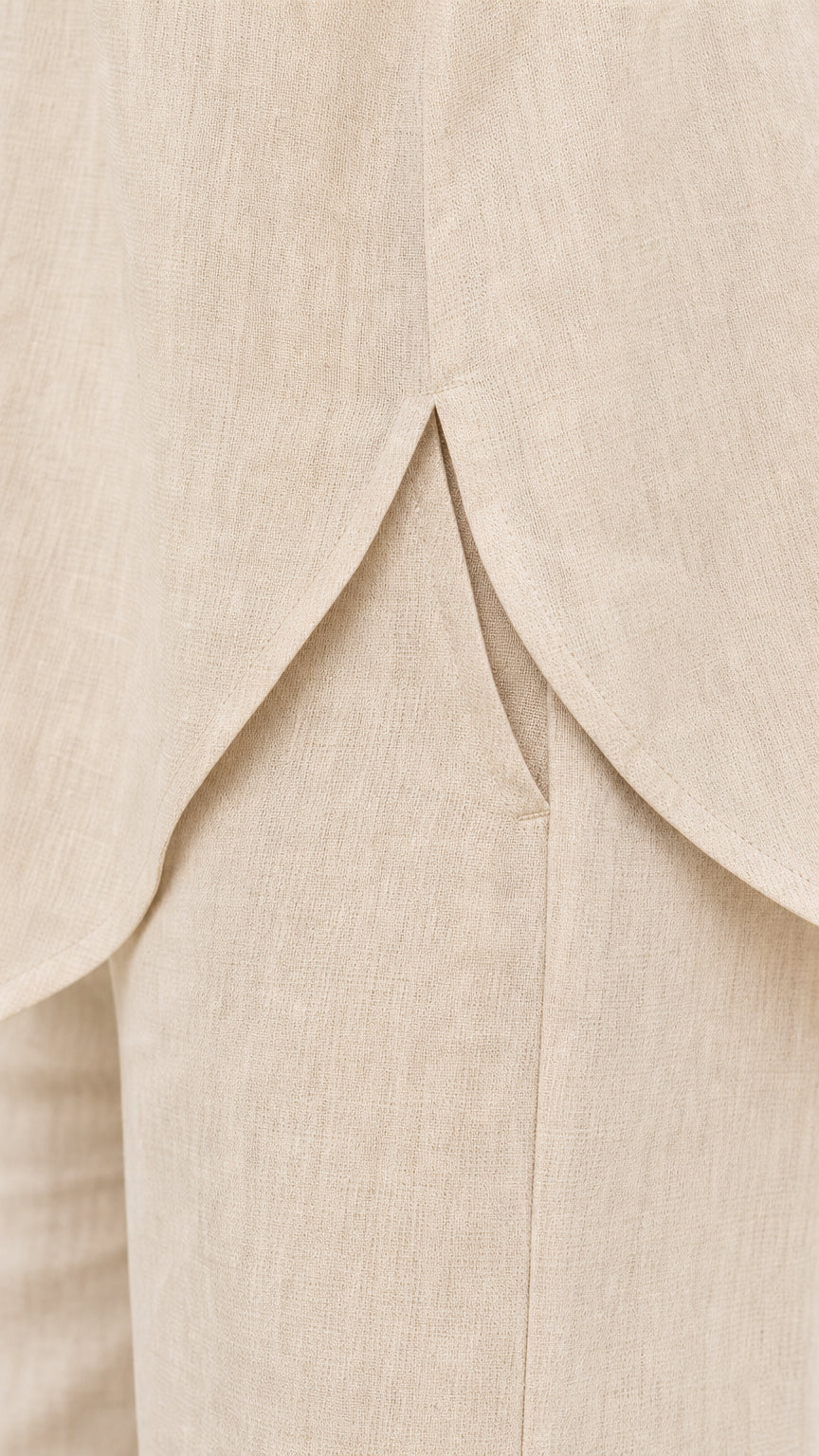 Close-up detail of back split hem on beige shirt and pants