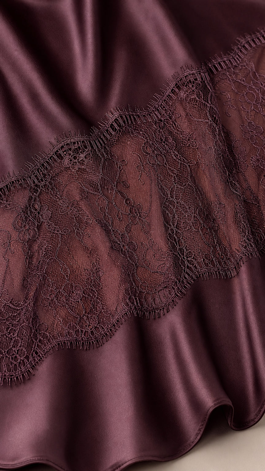 Close-up of plum satin fabric and intricate floral eyelash lace detailing
