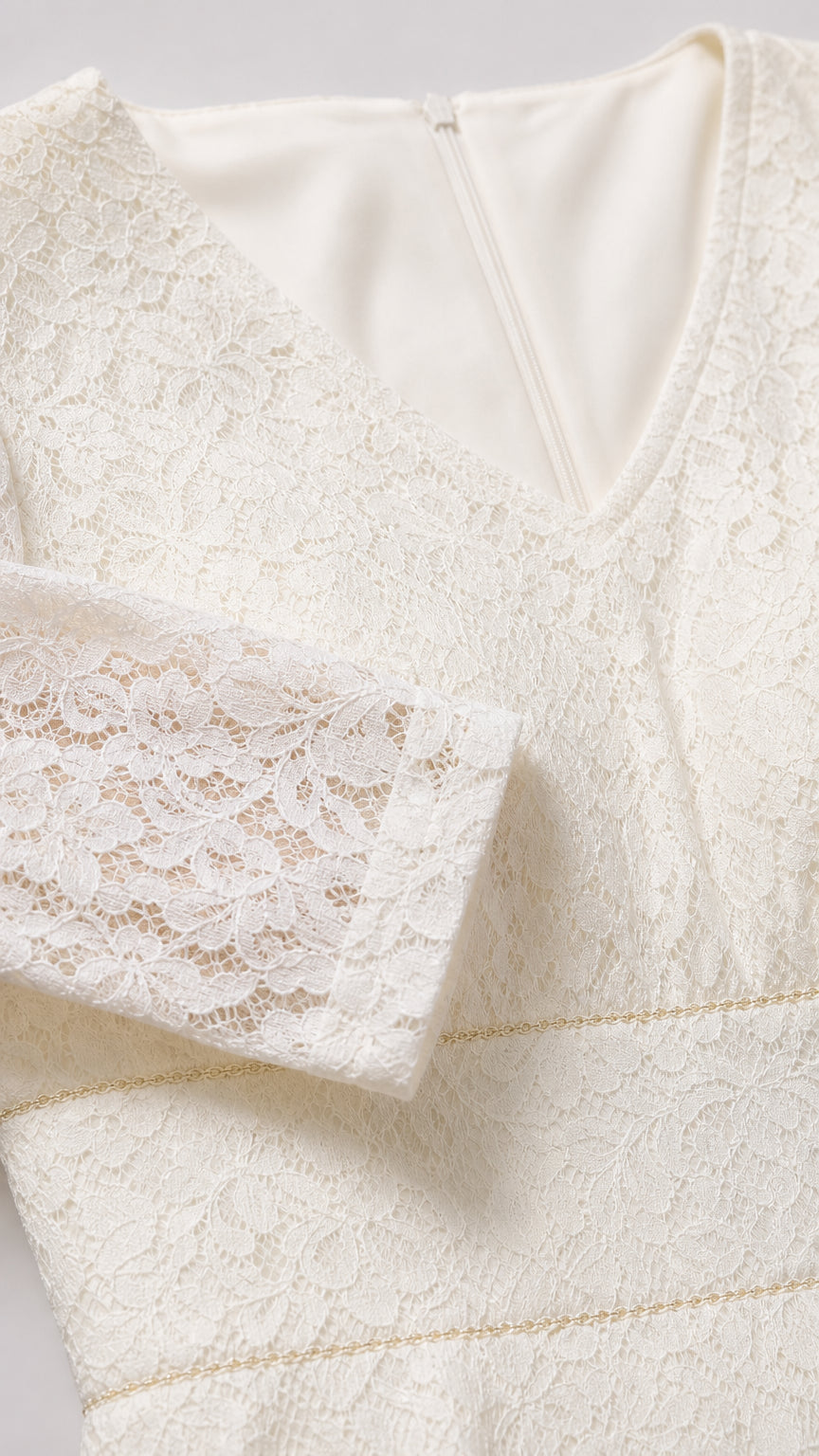 Close-up detail of ivory lace fabric texture, neckline, and waistband trim