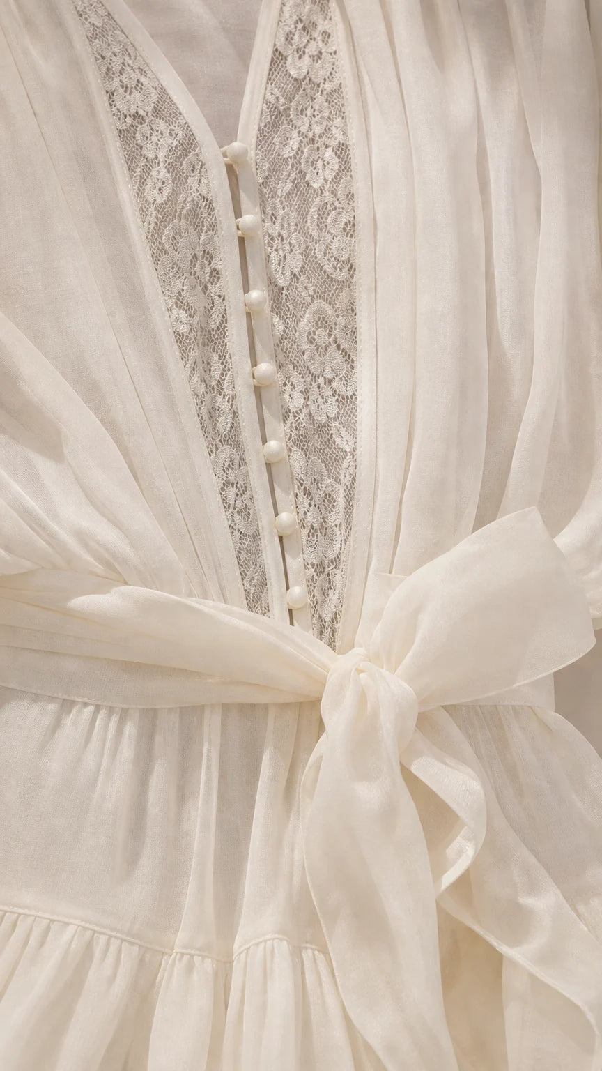 Close up of bodice buttons, lace, and tie belt on ivory romper