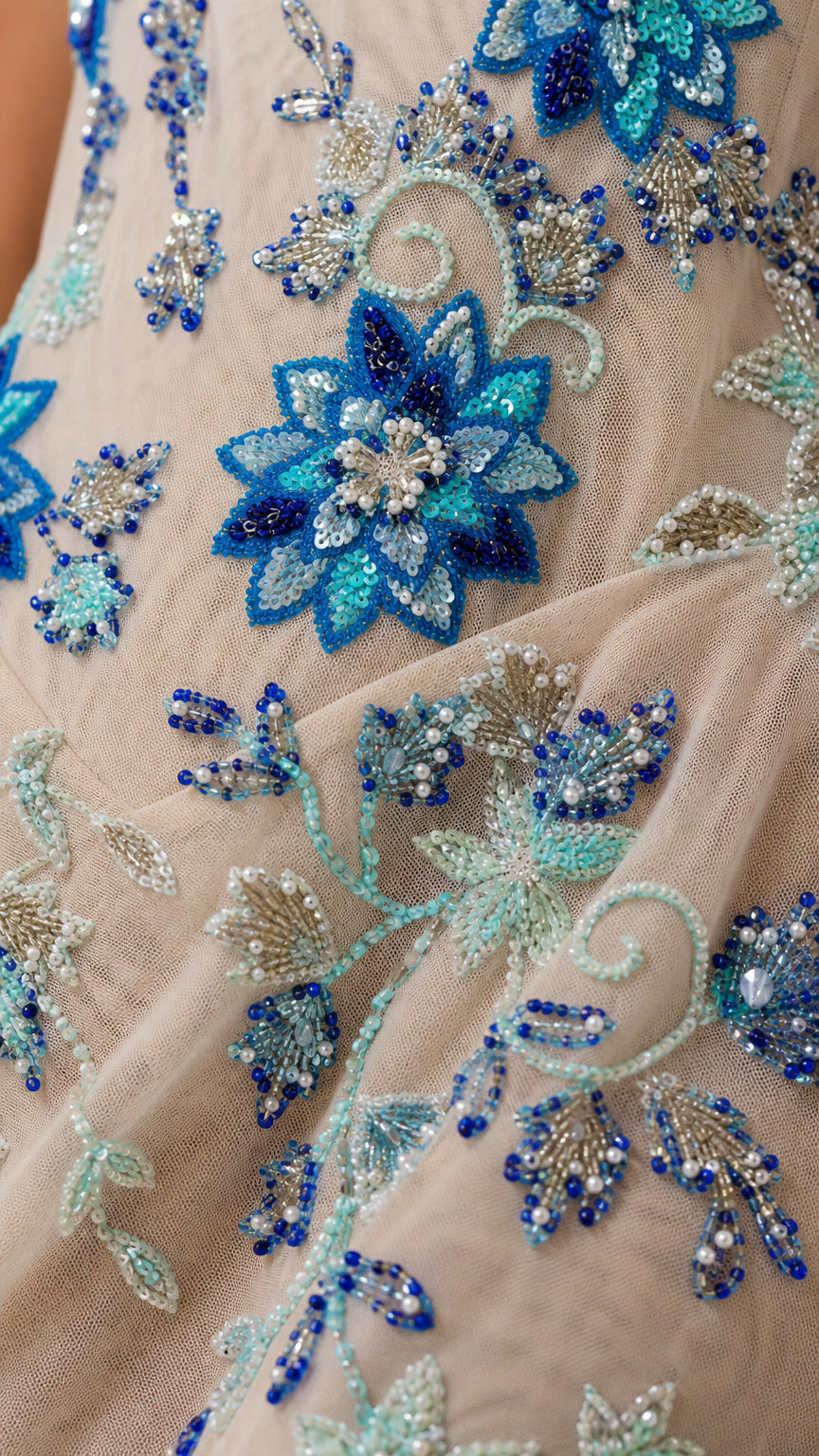 Close-up detail of intricate blue floral beading and embroidery on sheer mesh