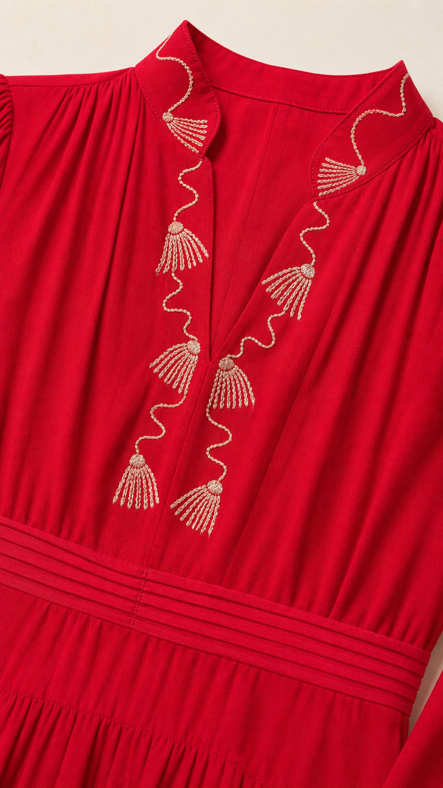 Close up view of gold-tone embroidery along V-neckline on red dress