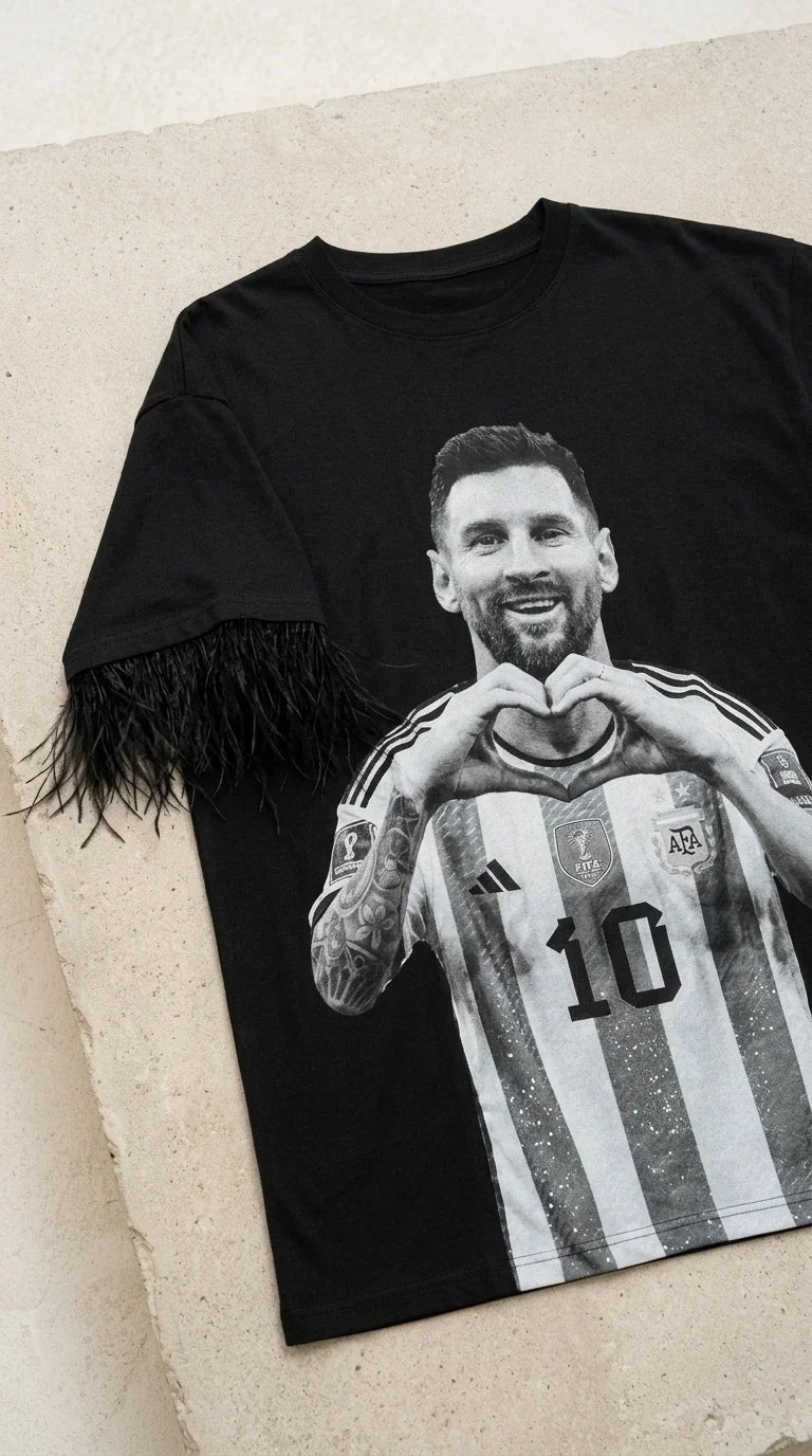 Flat lay detail view of black t-shirt dress showing graphic print and feather sleeve