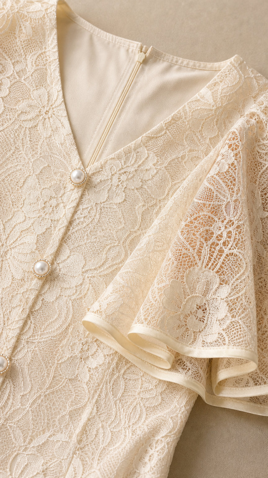 Close-up detail of V-neckline, lace texture, and pearl buttons on Ivory dress