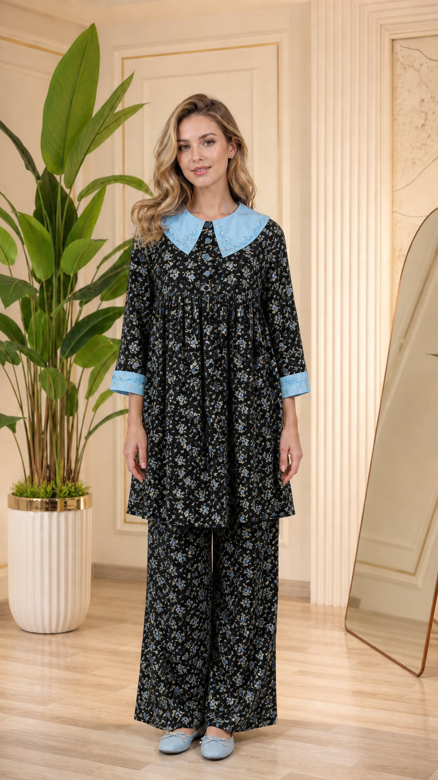 Model wearing black floral pajama set with light blue contrast collar and cuffs