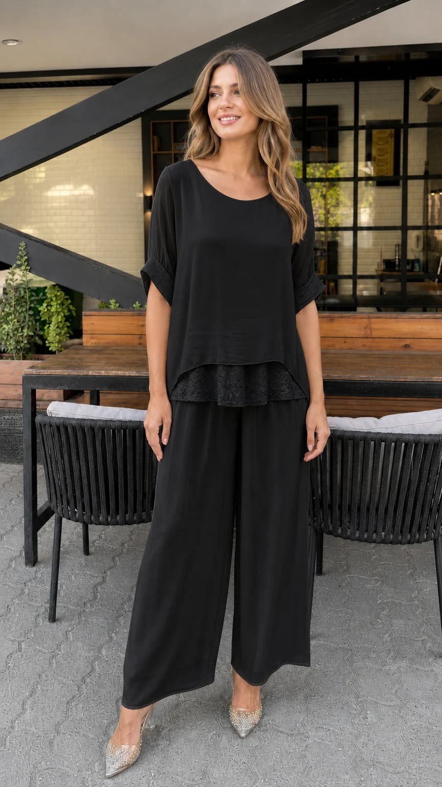 Model wearing black layered tunic and wide-leg pants set