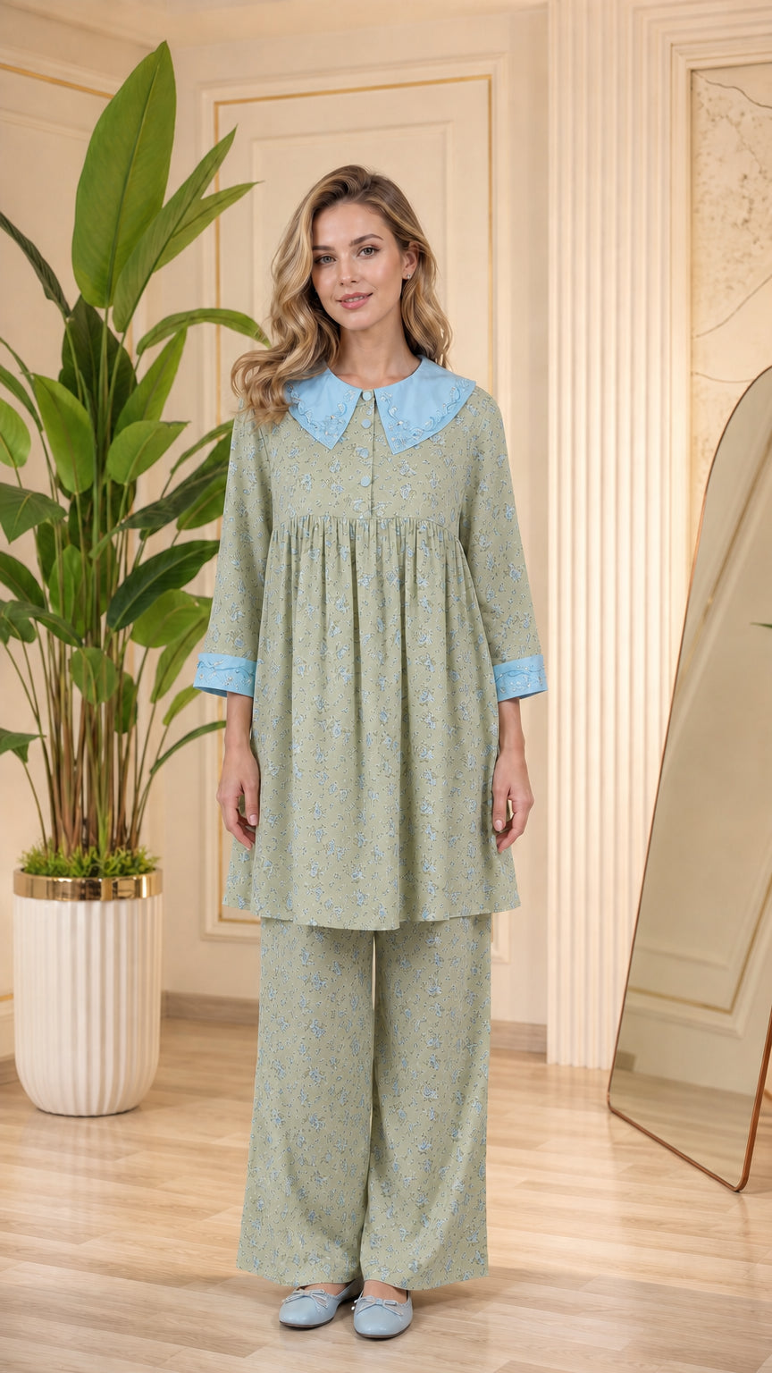 Model wearing sage green floral pajama set with light blue contrast collar and cuffs