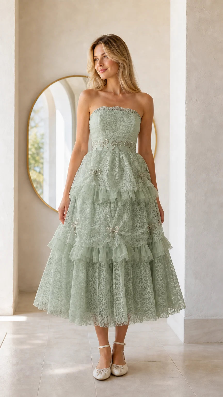 Front full view of woman wearing sage green strapless tiered midi dress