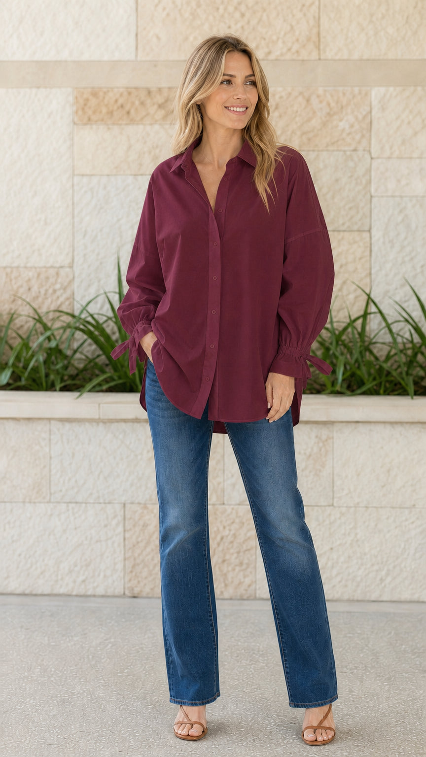 Woman wearing burgundy oversized button-down shirt with tie cuffs